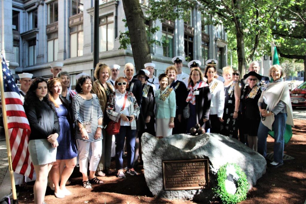 Members in Downtown Seattle posing around a historic monument after restoring the monument.