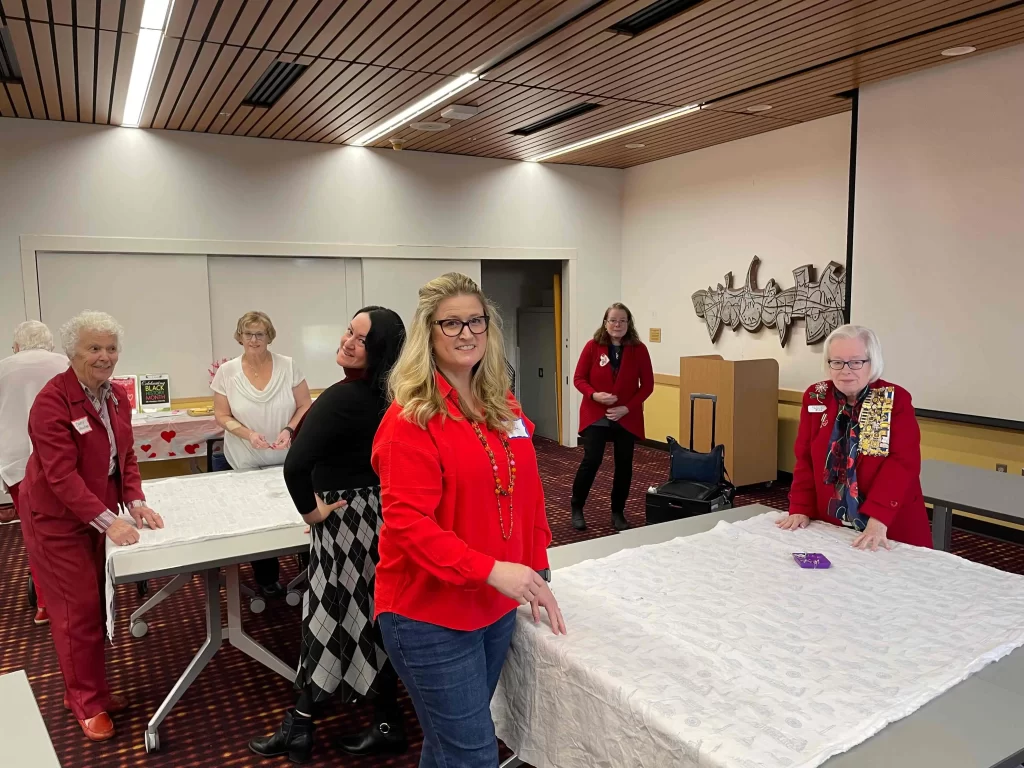 Members at a monthly chapter meeting doing an arts and crafts project that involves making quilts.